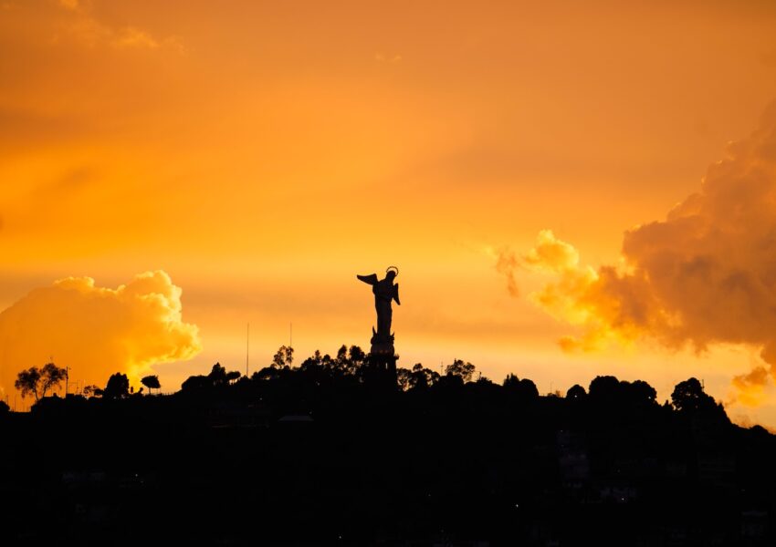 a statue is silhouetted against an orange sky